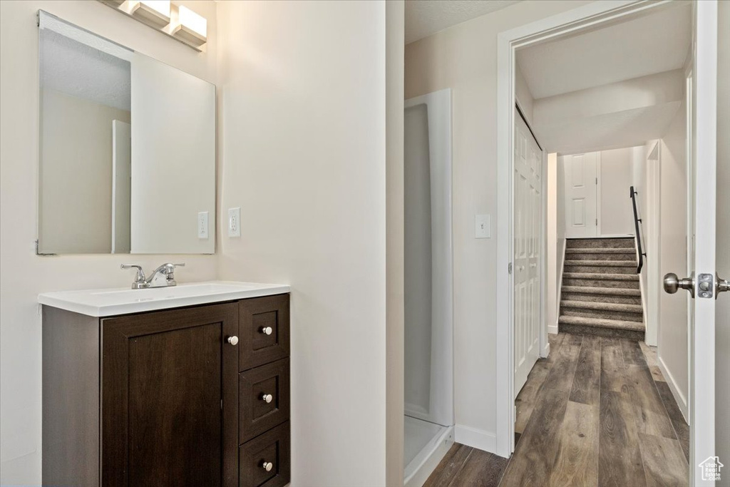 Full bathroom featuring vanity, wood finished floors, baseboards, and a shower