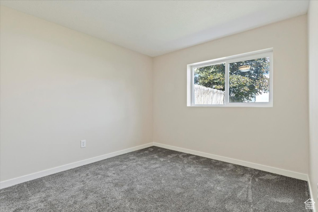 Unfurnished room with dark colored carpet and baseboards