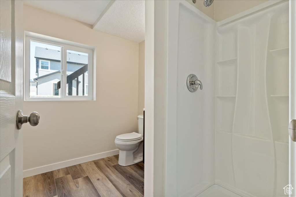 Full bathroom with a shower, wood finished floors, toilet, and baseboards
