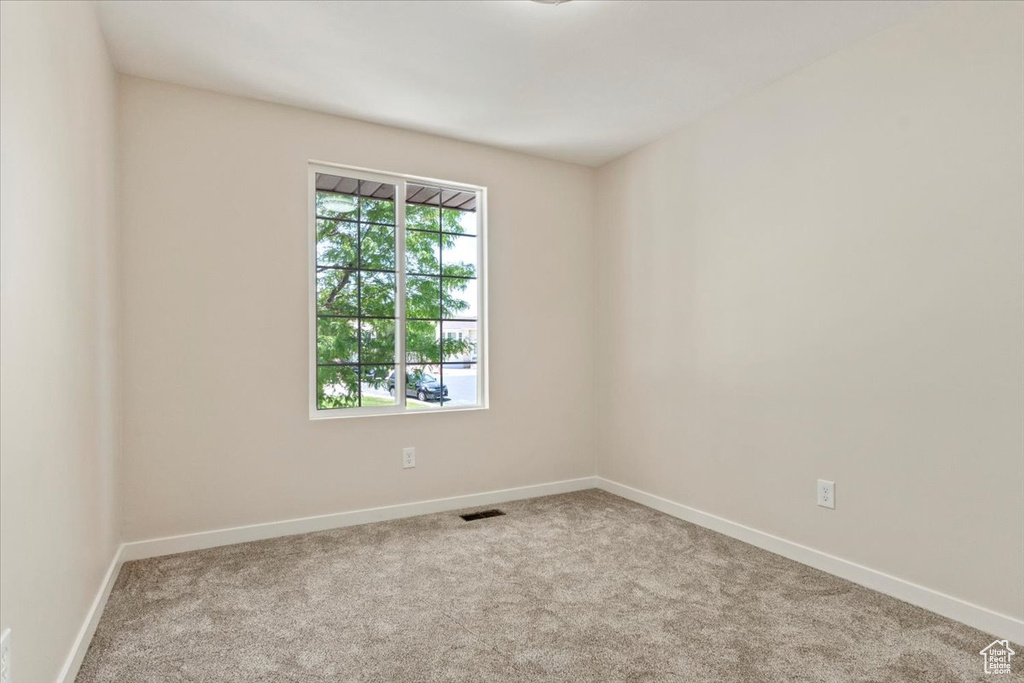 Carpeted spare room featuring baseboards