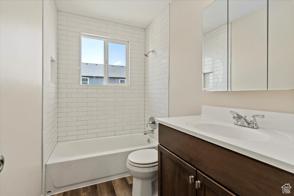 Bathroom with wood finished floors, vanity, toilet, and tub / shower combination