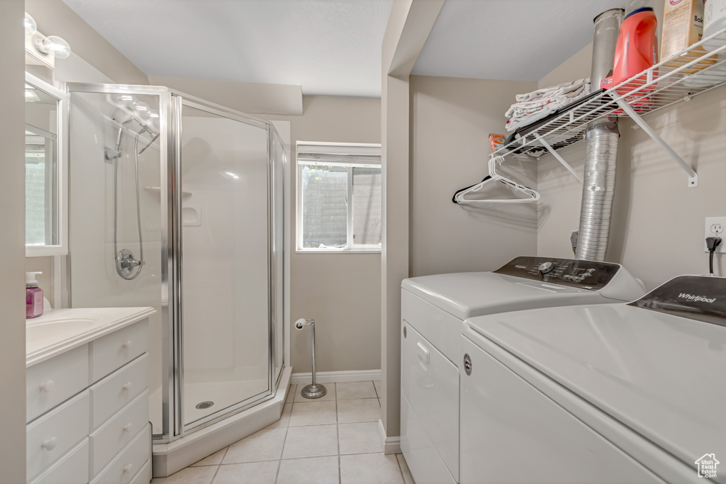 Bathroom featuring independent washer and dryer, a stall shower, tile patterned floors, vanity, and baseboards