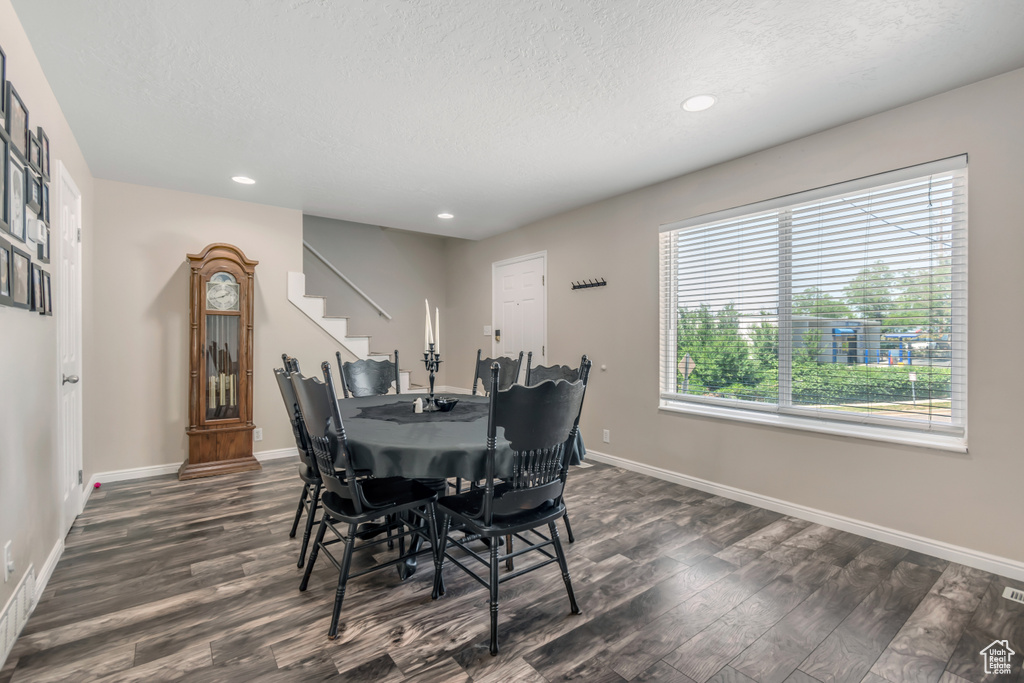 Dining space featuring dark wood-type flooring, a textured ceiling, recessed lighting, baseboards, and stairs