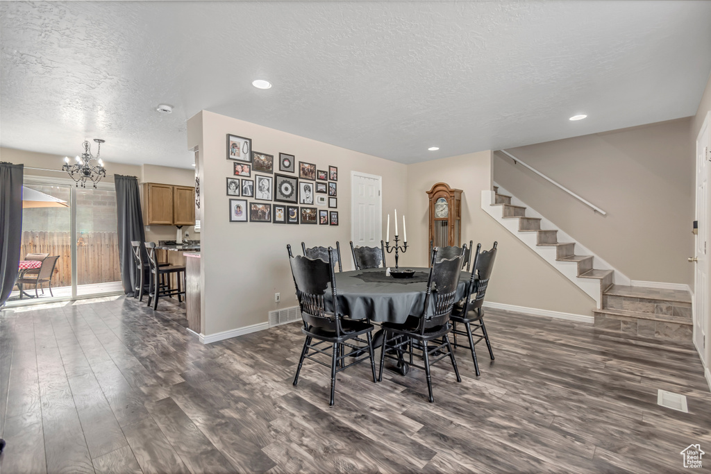 Dining room with a chandelier, a textured ceiling, dark wood finished floors, baseboards, and recessed lighting