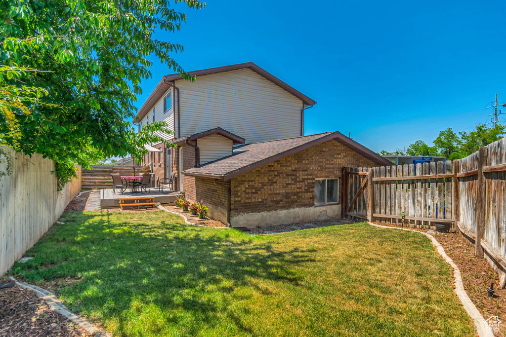 Back of property with brick siding, roof with shingles, and a deck