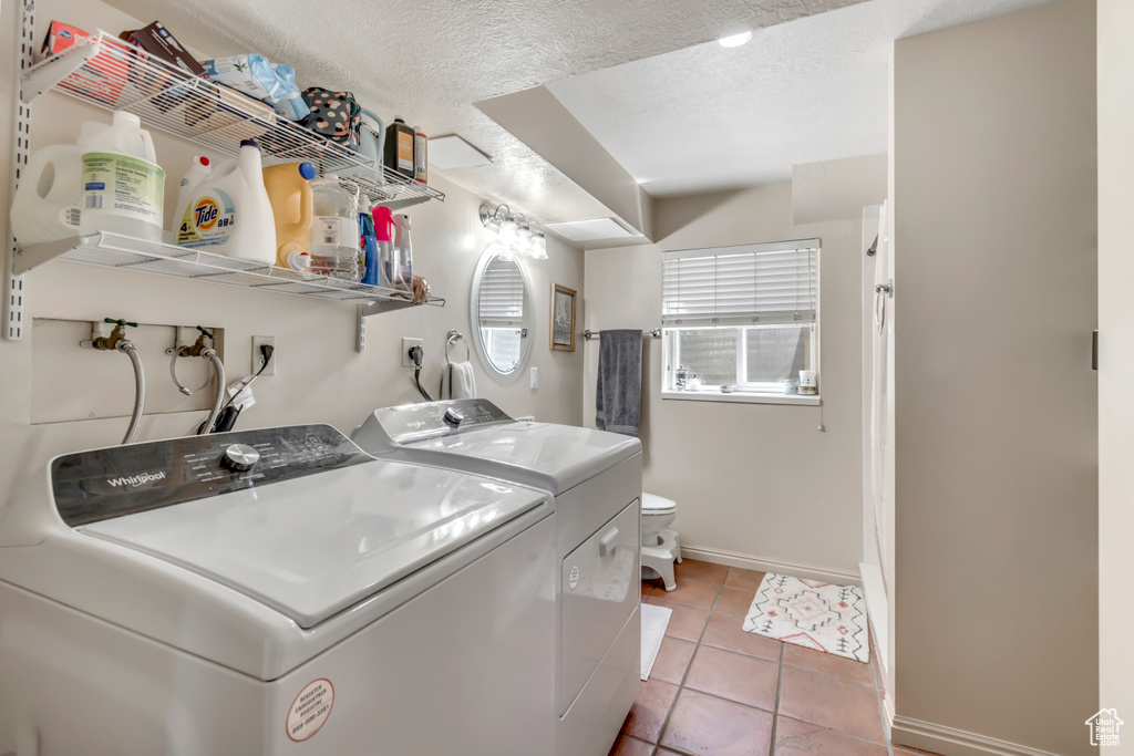 Laundry area with baseboards, washing machine and clothes dryer, light tile patterned floors, and a textured ceiling