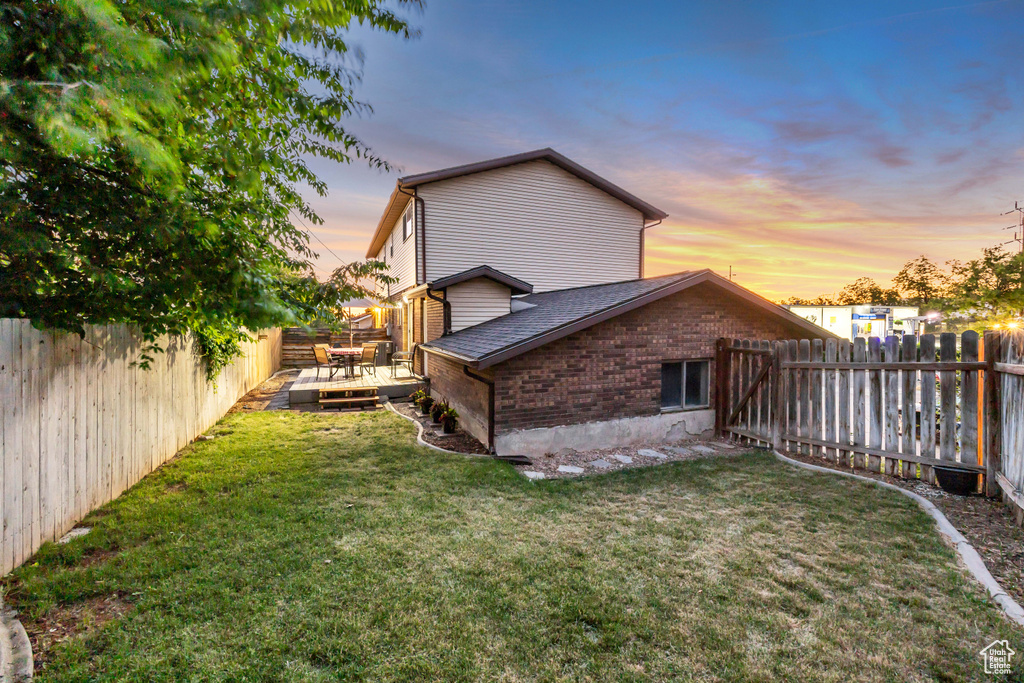 Back of property with a deck, brick siding, and roof with shingles