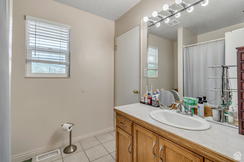 Bathroom with vanity, tile patterned floors, and baseboards