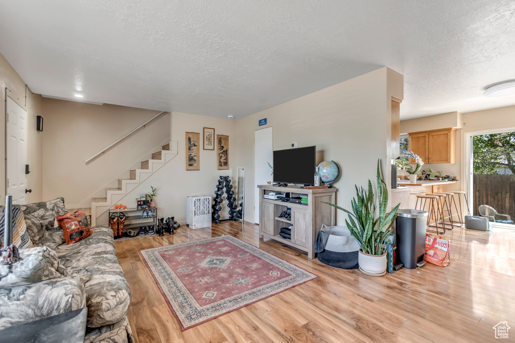 Living area featuring a textured ceiling, wood finished floors, and stairway