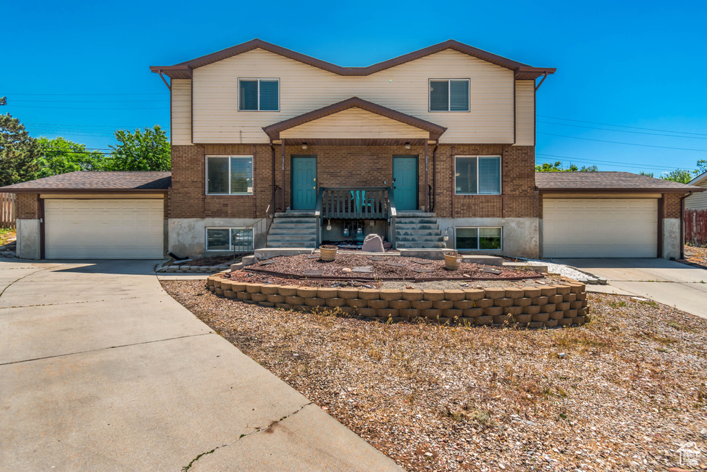 View of front facade featuring brick siding, concrete driveway, a porch, stairs, and an attached garage