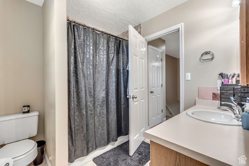 Full bath with vanity, toilet, a shower with curtain, and a textured ceiling
