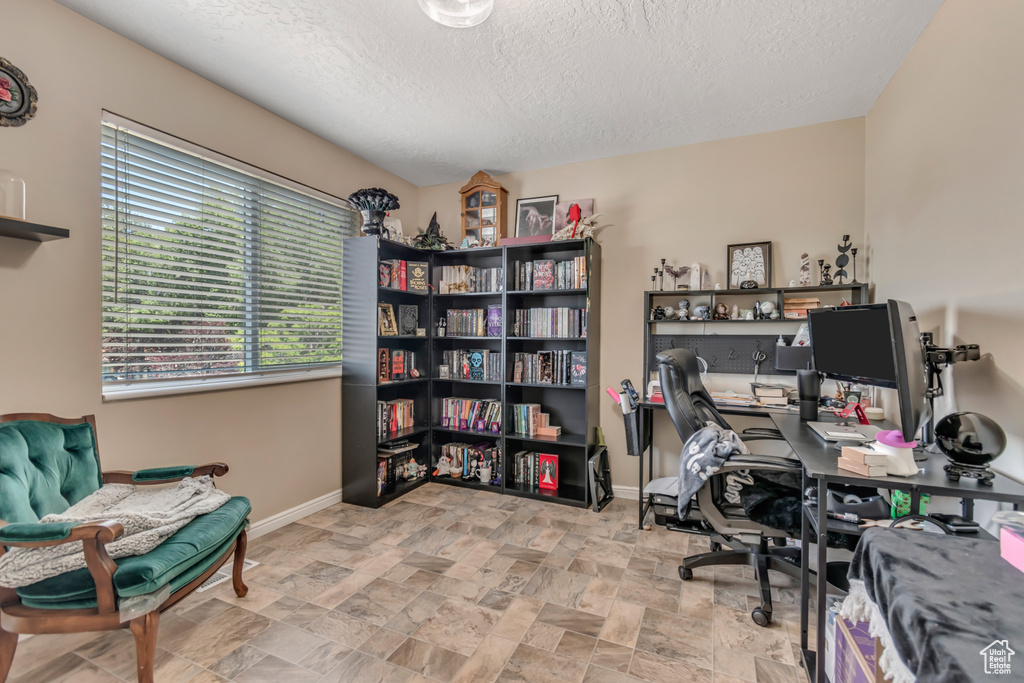 Office featuring a textured ceiling, baseboards, and stone finish flooring
