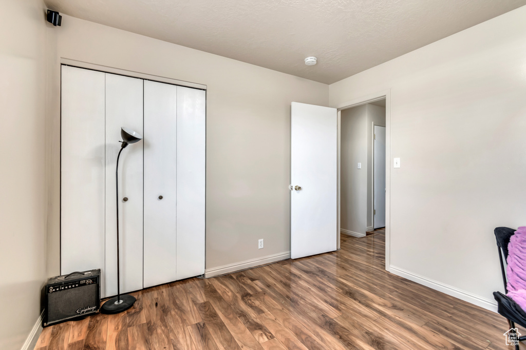 Unfurnished bedroom featuring wood finished floors, baseboards, and a closet