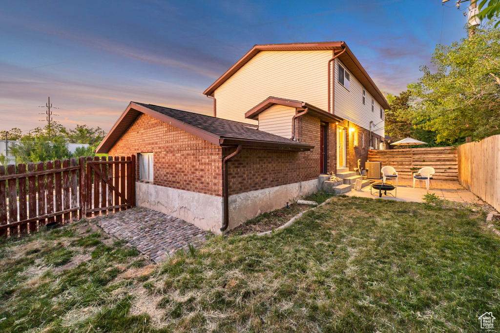 Property exterior at dusk featuring brick siding, a patio area, and central air condition unit