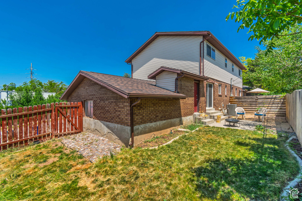 Rear view of house with brick siding, entry steps, a patio area, central air condition unit, and roof with shingles