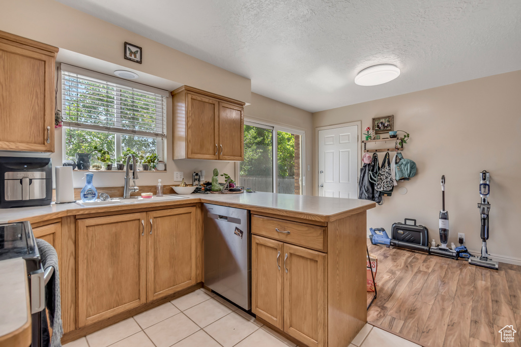 Kitchen featuring stainless steel appliances, a peninsula, a sink, light countertops, and a textured ceiling