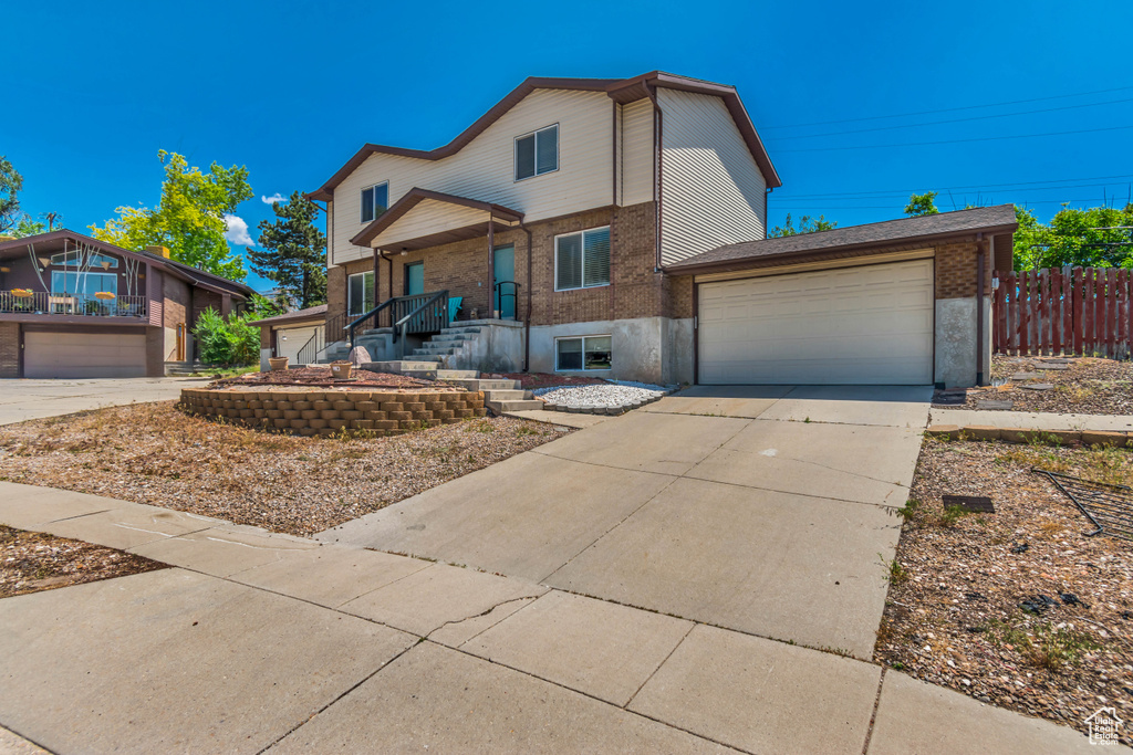 View of front of property with brick siding, driveway, and an attached garage