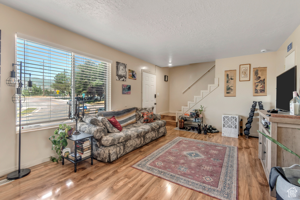 Living area with a textured ceiling, stairs, wood finished floors, and baseboards