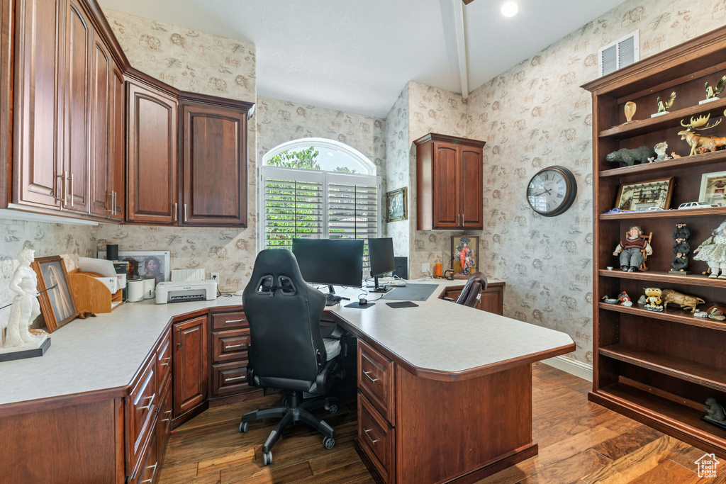 Office with wallpapered walls and dark wood finished floors