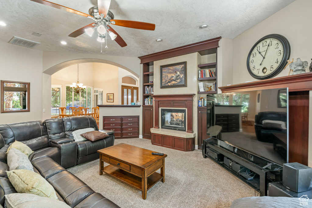 Living room with arched walkways, light colored carpet, a ceiling fan, a chandelier, and recessed lighting