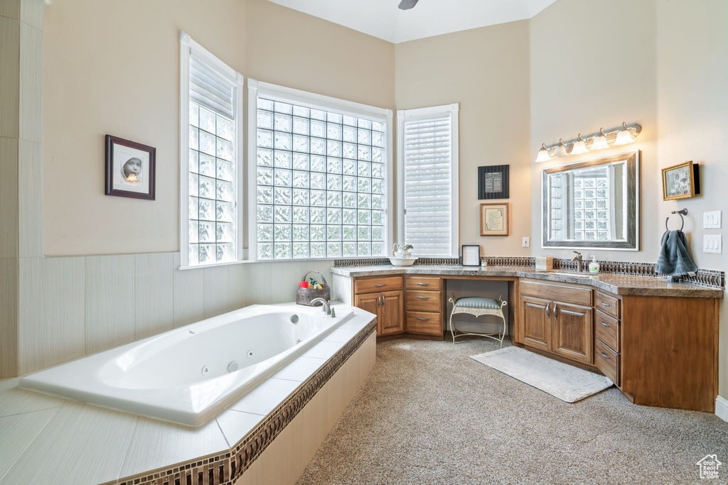 Bathroom with vanity, a tub with jets, and a wainscoted wall