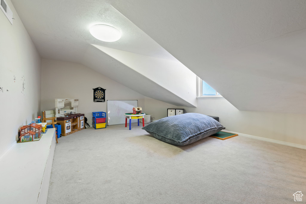 Carpeted bedroom with vaulted ceiling and baseboards