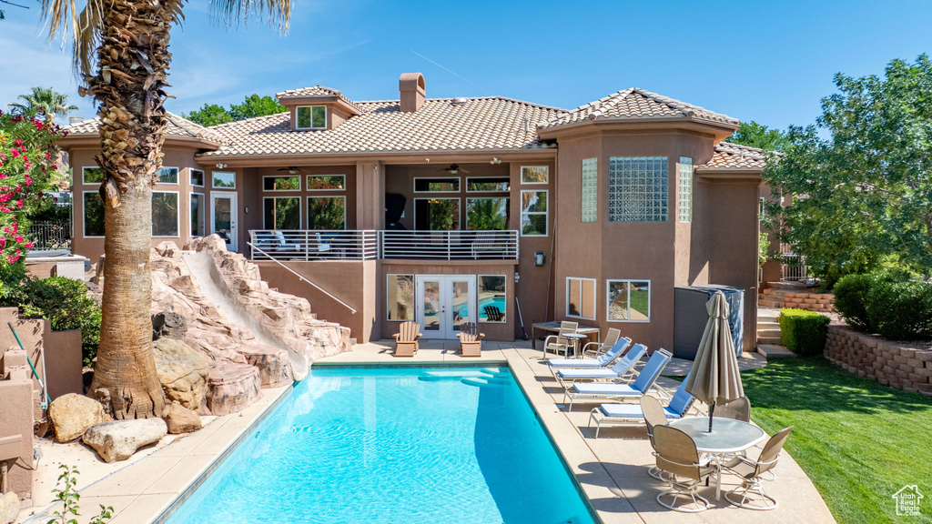 Back of house featuring french doors, a ceiling fan, a tile roof, and stucco siding