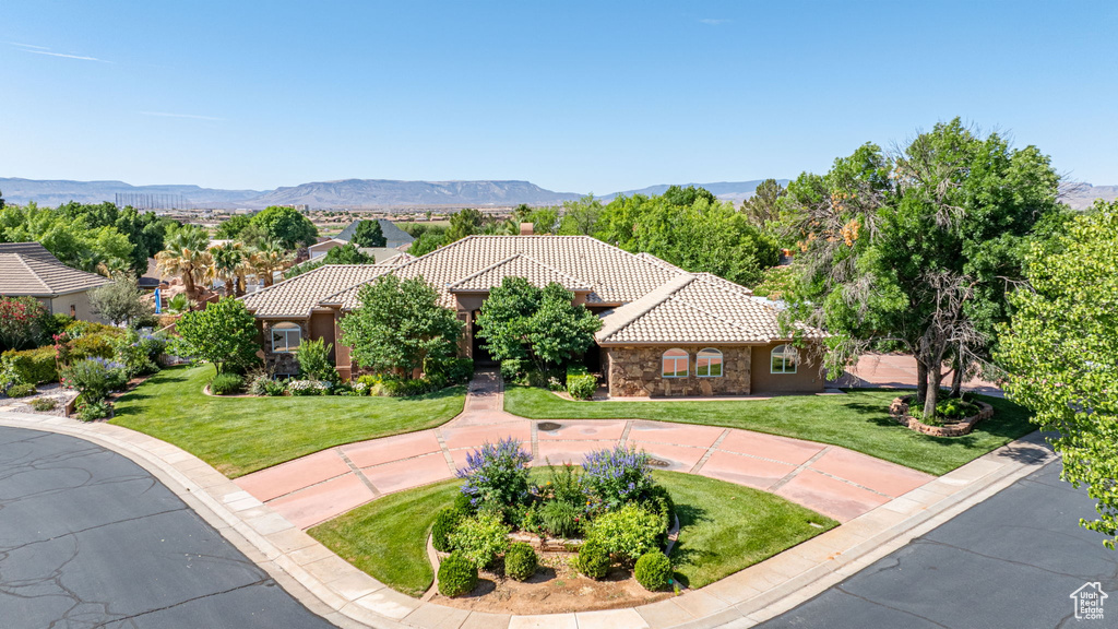 Mediterranean / spanish home featuring a tiled roof, a front yard, stone siding, and a mountain view