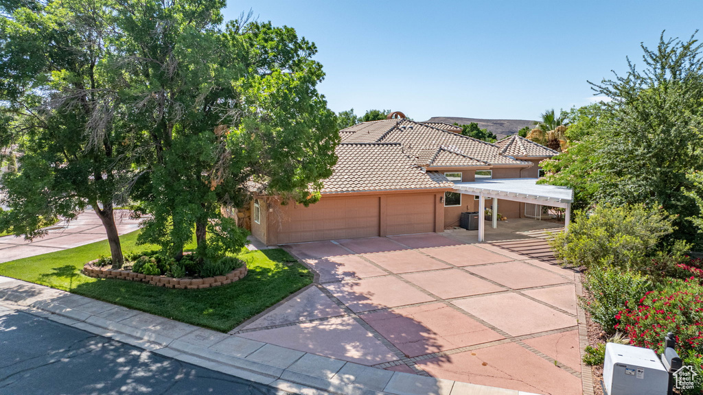View of front facade featuring a tiled roof, an attached garage, driveway, and stucco siding