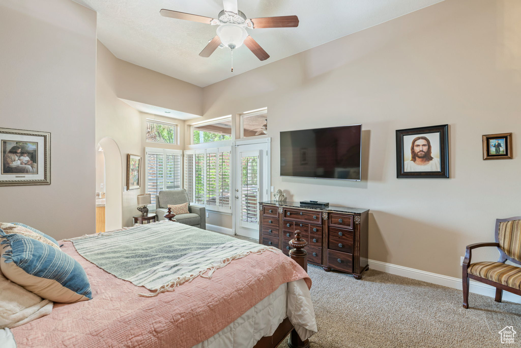 Carpeted bedroom featuring access to outside, a high ceiling, arched walkways, and ceiling fan