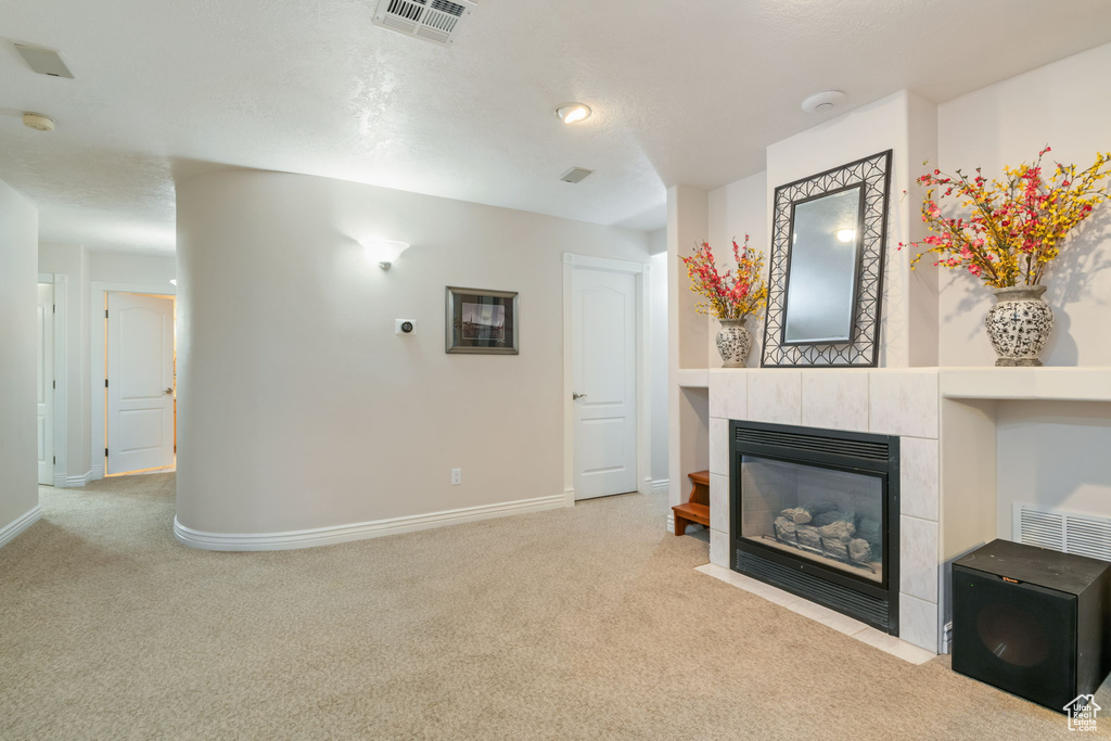 Unfurnished living room featuring carpet flooring and a tile fireplace