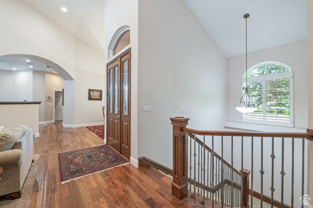 Entryway with high vaulted ceiling, wood-type flooring, and arched walkways