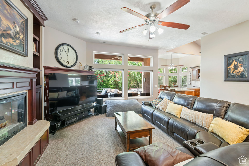 Carpeted living room featuring ceiling fan and a glass covered fireplace