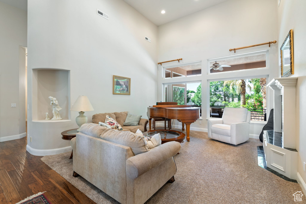 Living room featuring a high ceiling, a ceiling fan, wood finished floors, and recessed lighting