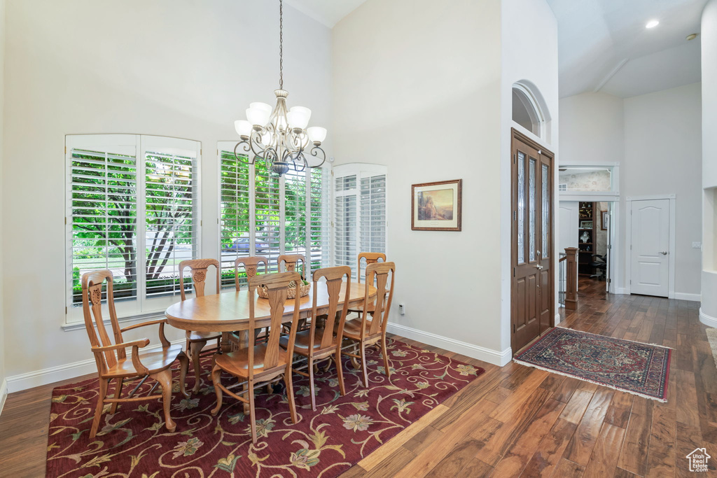 Dining area with high vaulted ceiling, a chandelier, and wood finished floors