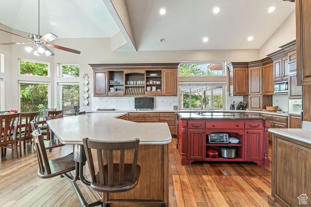 Kitchen with open shelves, stainless steel microwave, a center island, a ceiling fan, and tasteful backsplash