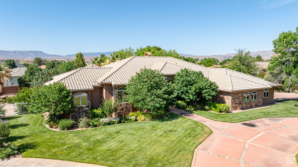 View of front of property with stone siding, a tiled roof, a front lawn, and a mountain view