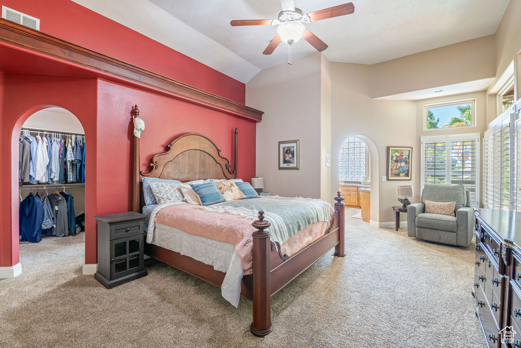Bedroom featuring carpet floors, a walk in closet, a ceiling fan, a closet, and arched walkways