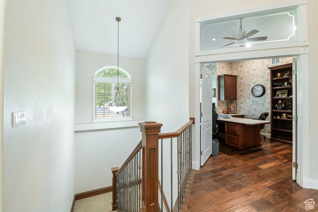 Corridor with dark wood finished floors, an upstairs landing, high vaulted ceiling, an office area, and a chandelier