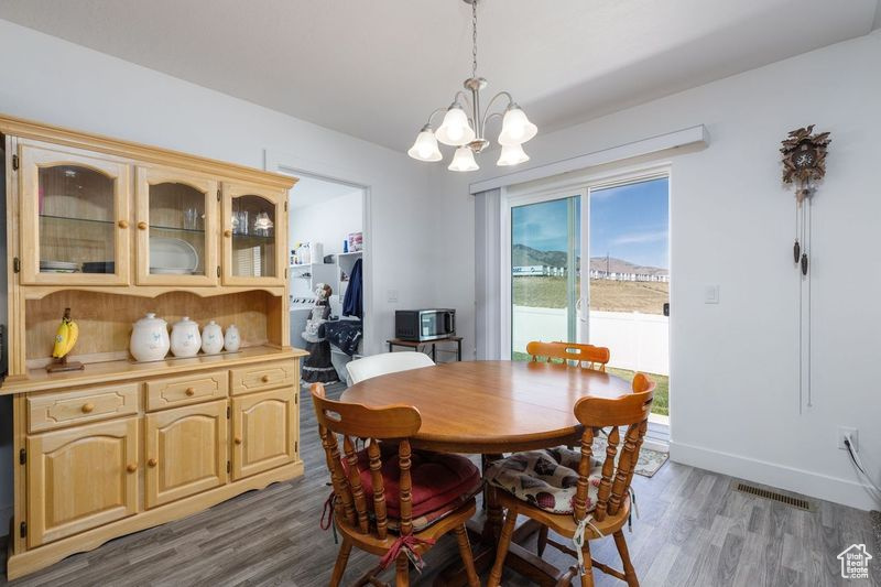 Dining space with a chandelier, wood finished floors, and baseboards