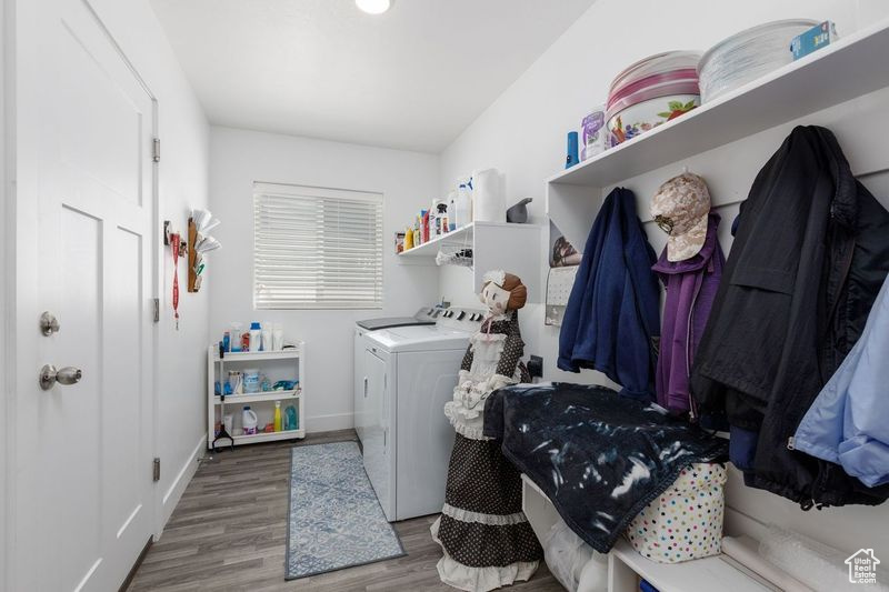 Washroom with washing machine and clothes dryer, wood finished floors, and baseboards