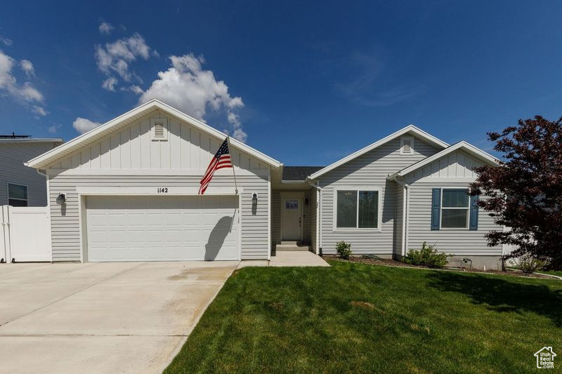 Single story home featuring board and batten siding, a garage, and concrete driveway