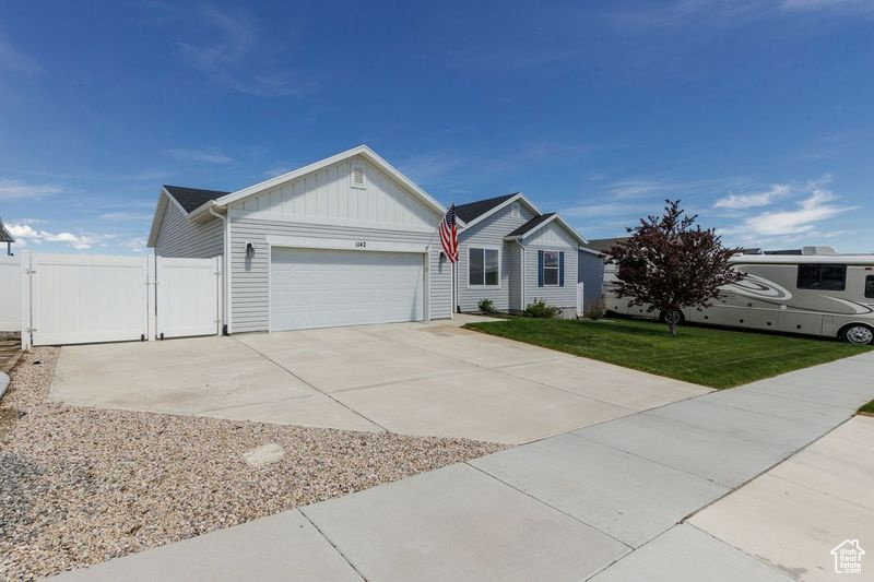 Ranch-style home with an attached garage, board and batten siding, a gate, and concrete driveway