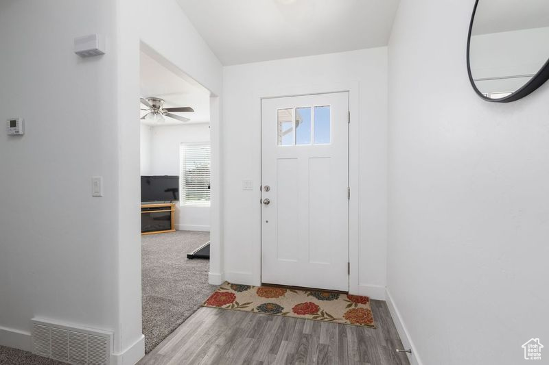 Foyer entrance with wood finished floors, baseboards, and ceiling fan