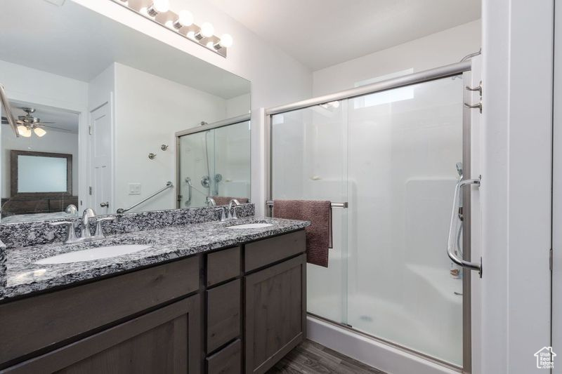 Full bath with a stall shower, wood finished floors, double vanity, and ceiling fan
