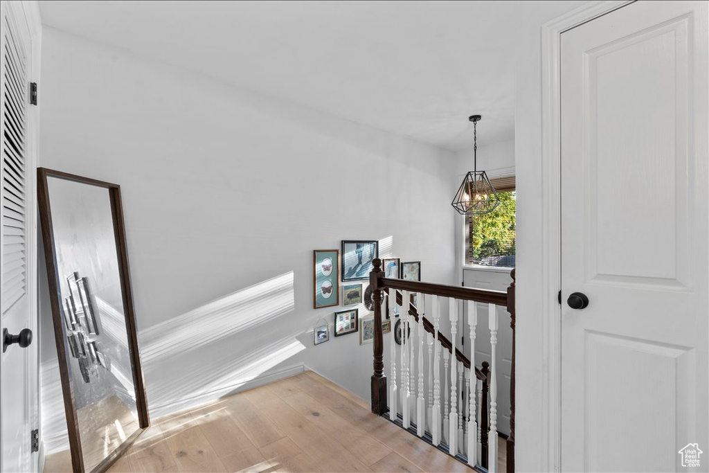Stairs featuring wood finished floors, a chandelier, and baseboards