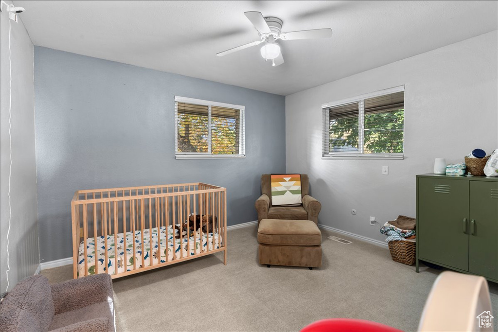 Bedroom featuring baseboards, a crib, carpet floors, and ceiling fan