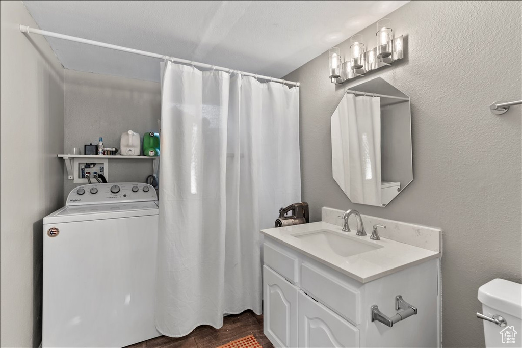 Bathroom featuring washer / clothes dryer, vanity, toilet, a shower with shower curtain, and wood finished floors