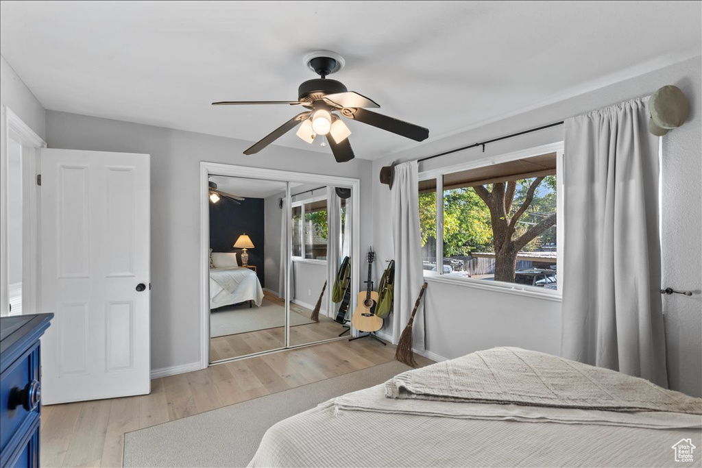 Bedroom with light wood finished floors, baseboards, and a ceiling fan