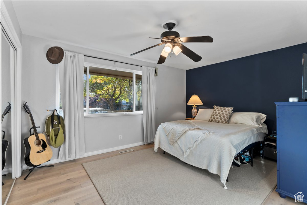 Bedroom with light wood-style floors, ceiling fan, baseboards, and a closet